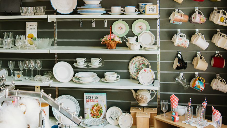 A wall of shelves carrying china, plates, mugs and glass items